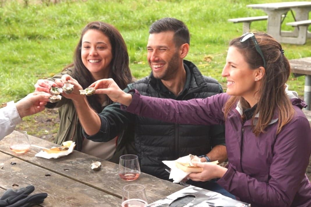 Three guests toast with freshly shucked oysters